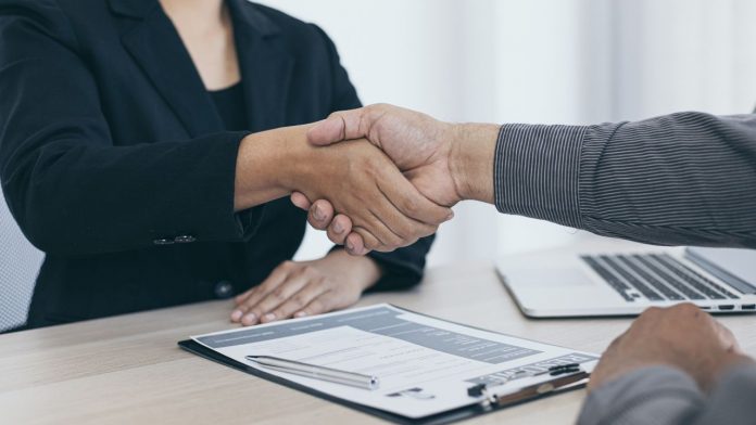 handshake over clipboard and next to laptop